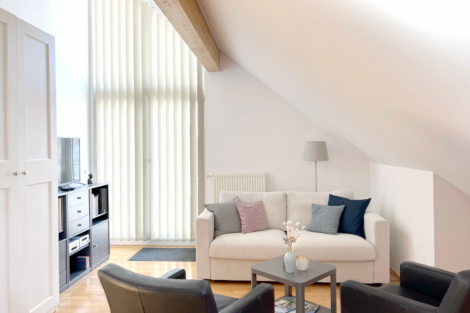 Wohnbereich mit Sofa, Sesseln und Stehlampe unter der Dachschräge
