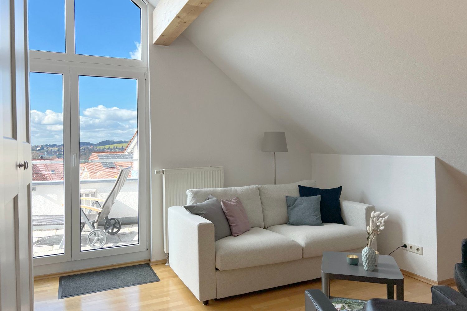 Wohnbereich mit hellem Sofa und Tür zur Dachterrasse
